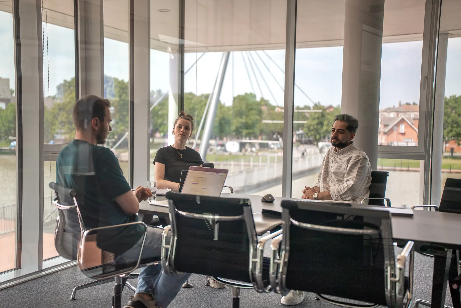 Besprechung an einem Tisch mit Laptop in einem hellen Büro